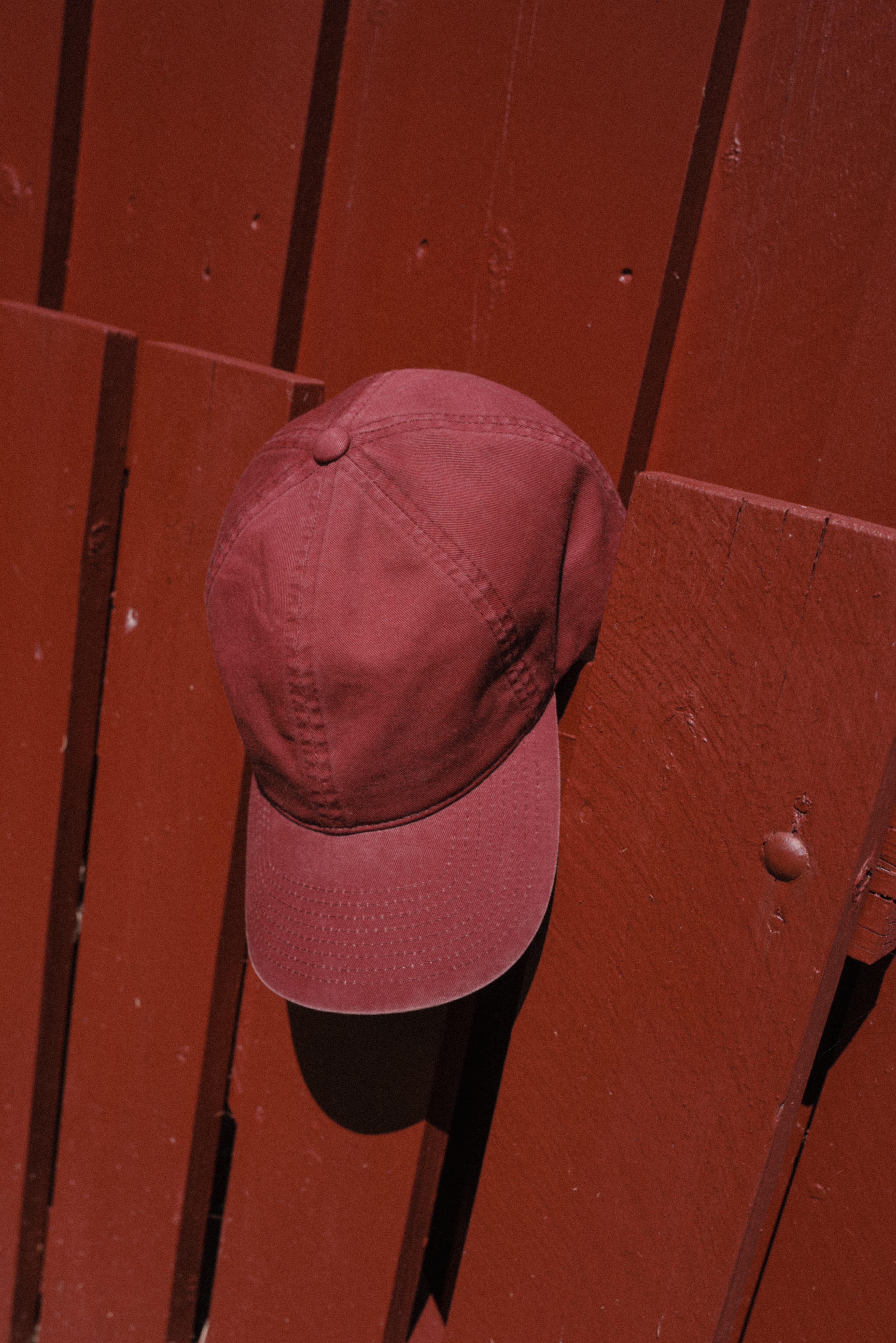 Washed cotton cap in burgundy by red painted wall